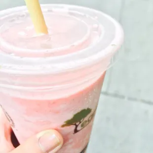 a hand holding a strawberry smoothie