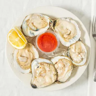 a plate of oysters with a side of ketchup