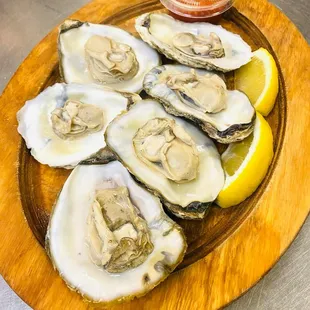 a plate of oysters with lemon wedges