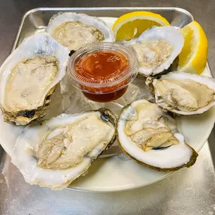 a plate of oysters with a side of ketchup