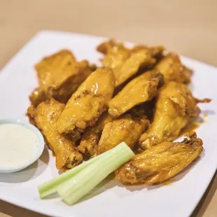 a plate of chicken wings with a dipping sauce