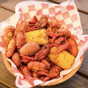 a basket of boiled crawfish, corn, and potatoes
