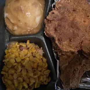 Fried Pork chops, mashed potatoes with gravy and fried corn.