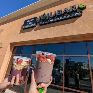 two people holding up cups of smoothie