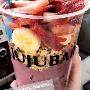 a person holding a cup of fruit and yogurt