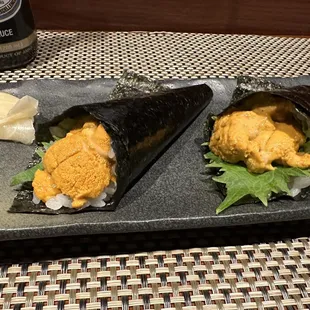 two sushi rolls on a black plate