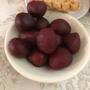 a bowl of plums and a piece of bread