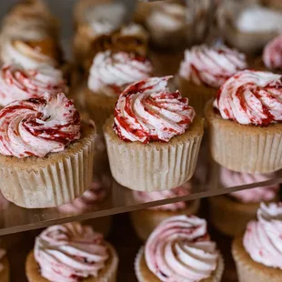 a display of cupcakes with red and white frosting