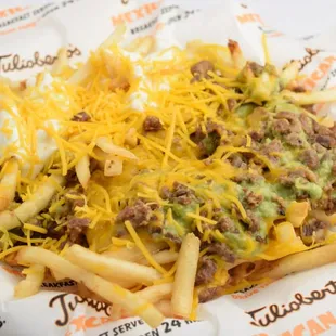 a plate of fries with cheese and guacamole