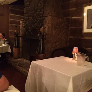 Stone fireplace against a rustic log wall.