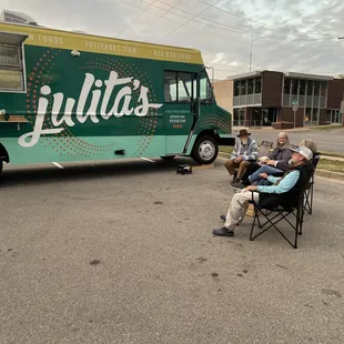 two people sitting in lawn chairs in front of a food truck