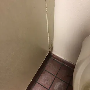 Nasty bathroom floor &amp; rusty stall wall.