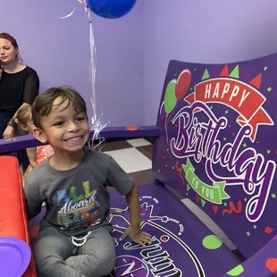 Happy birthday boy in the party room chair.