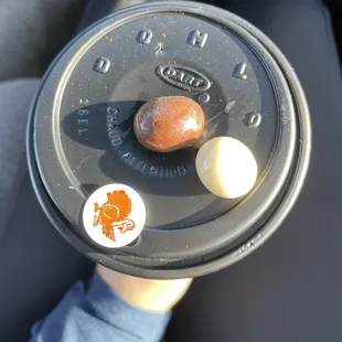 a person holding a donut in a plastic container