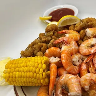 a plate of shrimp, corn, and potatoes