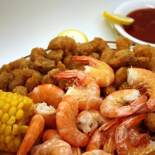 a plate of shrimp and corn with dipping sauce