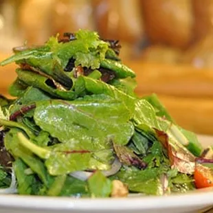 a plate of salad with bread in the background