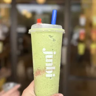 a hand holding a cup of matcha