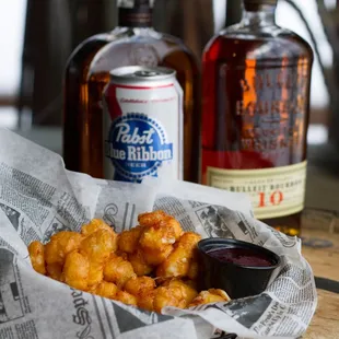 a basket of chicken nuggies and a bottle of bourbon