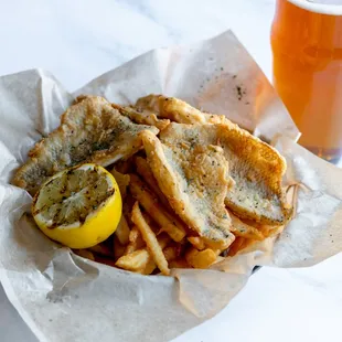 a basket of fish and chips with a glass of beer