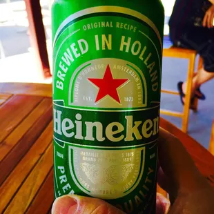 a hand holding a can of heineken