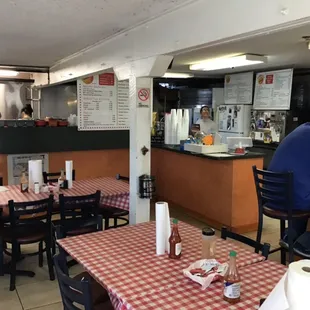 Dining room with the owner smiling behind the order counter.