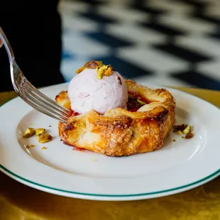 a person eating a pastry with a scoop of ice cream