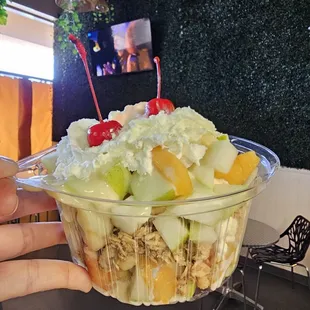 Fruit Salad - Pear, apple, mango, banana with ice cream in the middle topped with granola whip cream and cherry on top.