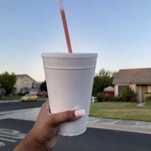 a hand holding a cup with a straw
