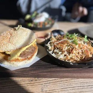 Breakfast Sandwich with Tabasco honey aioli on brioche bun with house potatoes.  sausage + egg + cheddar cheese