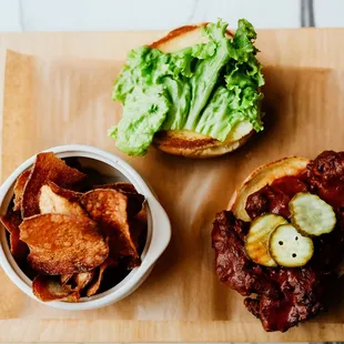 a burger and chips on a cutting board