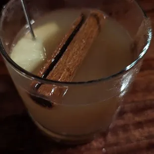 a glass of liquid with a cinnamon stick sticking out of it
