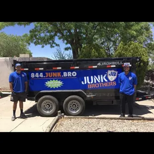 two men standing next to a junk truck