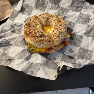 a bagel sandwich on a checkered paper wrapper