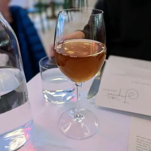 a glass of wine and a bottle of water on a table