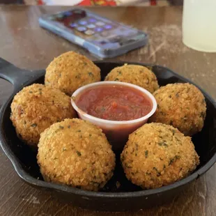  bowl of tomato sauce and a plate of fried meatballs