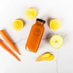 a bottle of juice surrounded by sliced oranges and lemons