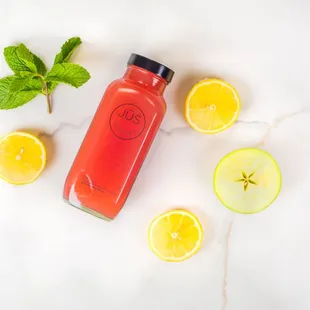 a bottle of juice surrounded by lemons and mint