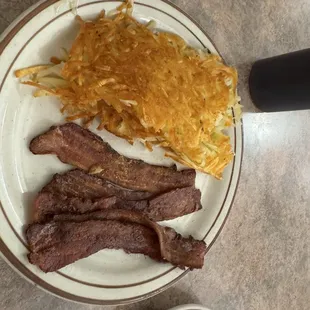 Sides of hash brown potatoes and bacon.