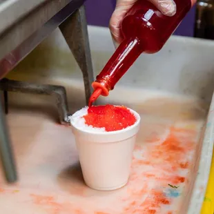 a person pouring ketchup into a cup