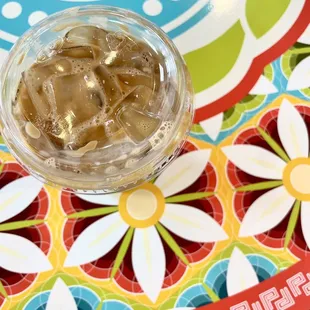 a glass of iced coffee on a colorful plate