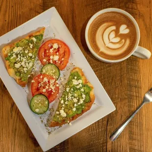 a plate of toast with avocado, tomato, and cucumber