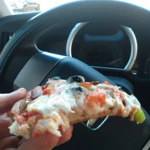 a hand holding a slice of pizza