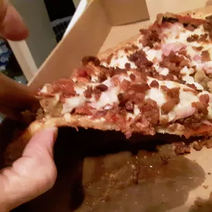 a person taking a slice of pizza