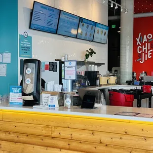 a restaurant counter with a menu on the wall