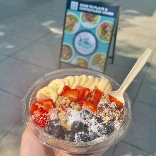 a hand holding a bowl of fruit