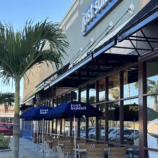 the outside of a restaurant with tables and umbrellas