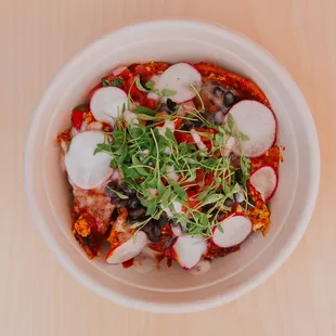 Chilaquiles bowl: corn tortilla chips with tofu egg scramble or just egg, salsa soda, blackens, pico de Gallo, radish and micro cilantro.