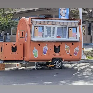 an orange food truck parked on the side of the road