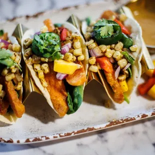 a plate of tacos with a side of mango salsa